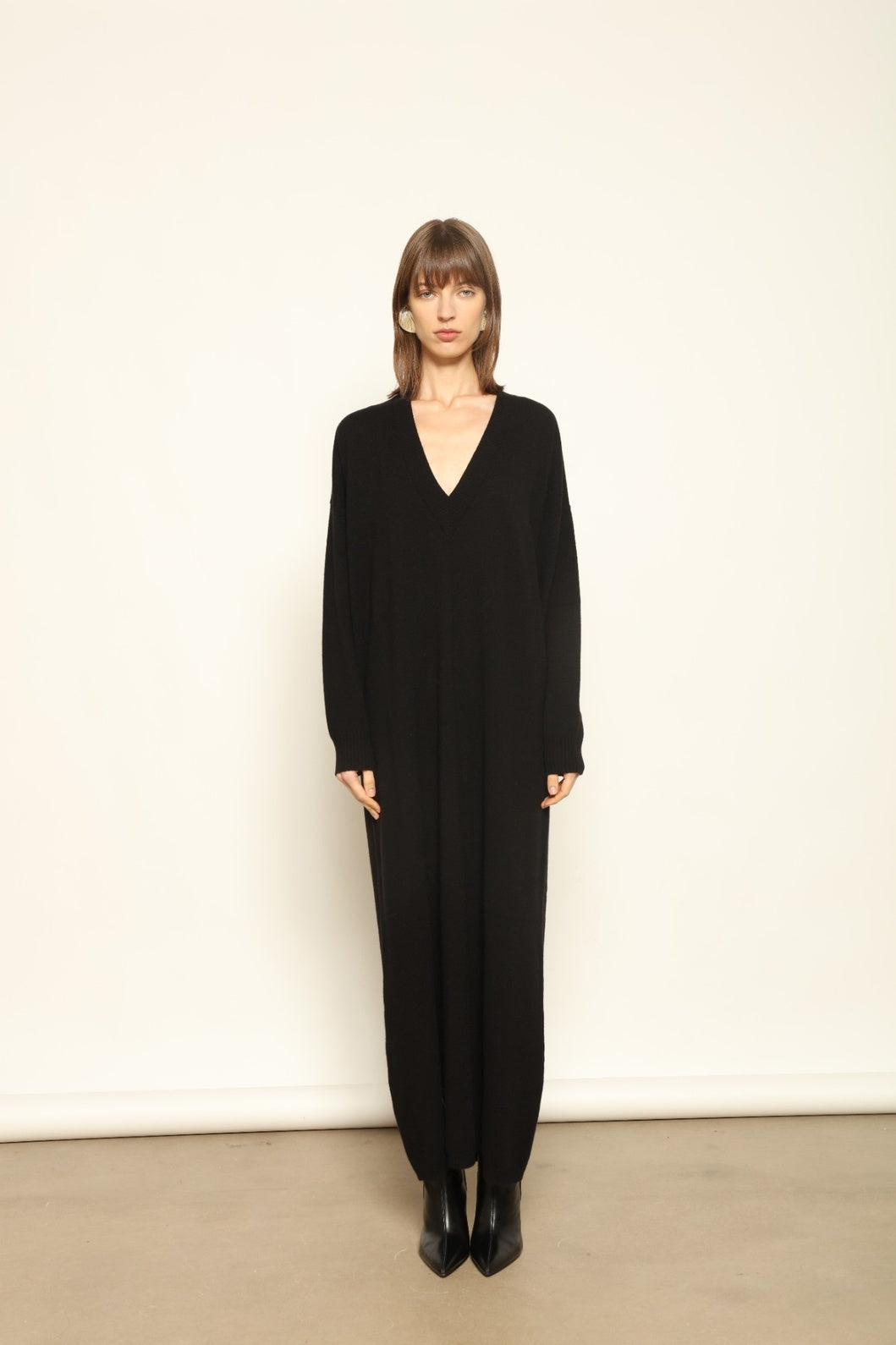 Model wearing the Black Katharina V-Neck Cashmere Maxi Dress by House of Woven Stories, crafted in Italy from 100% pure Inner Mongolia cashmere, featuring a flowing silhouette, soft drape, and timeless sustainable black knitwear design