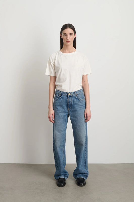 Model is wearing Bec Cotton Jean Halle Wash by B Sides in pale blue stone washed cotton denim with mid-rise straight leg fit, zip fly and brass button closure, available at House of Nomad Stories