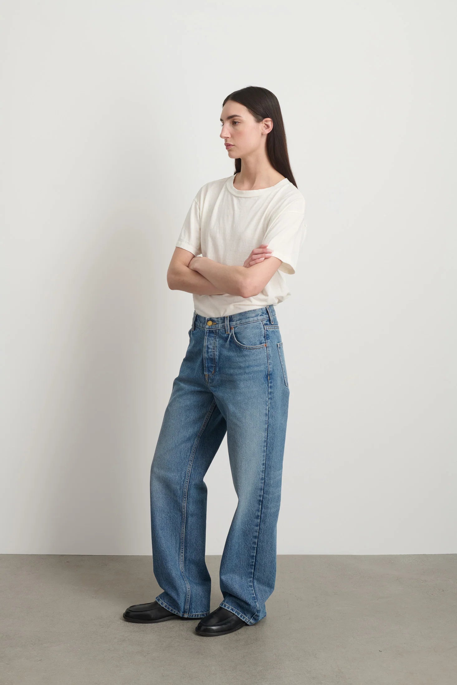 Model is wearing Bec Cotton Jean Halle Wash by B Sides in pale blue stone washed cotton denim with mid-rise straight leg fit, zip fly and brass button closure, available at House of Nomad Stories