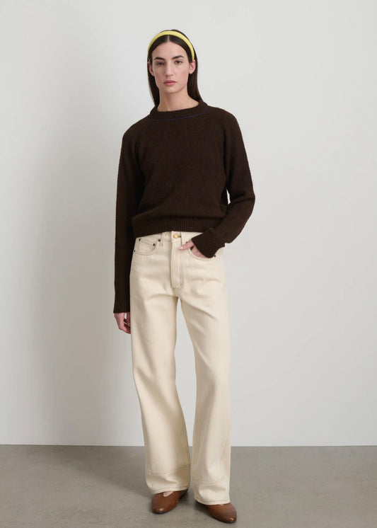 Model is wearing B Sides Charlot jeans, mid-rise relaxed straight denim in undyed cotton, with 5-pocket design, copper rivets, and brass logo button, part of the House of Woven Stories curated collection.