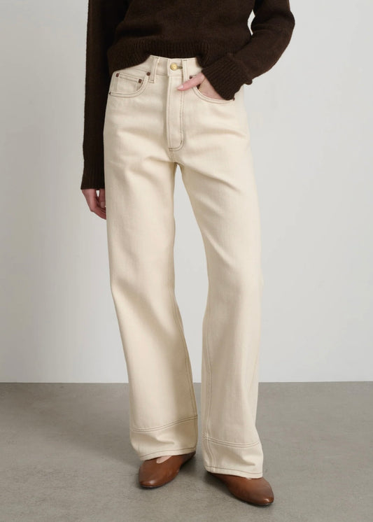 Model is wearing B Sides Charlot jeans, mid-rise relaxed straight denim in undyed cotton, with 5-pocket design, copper rivets, and brass logo button, part of the House of Woven Stories curated collection.