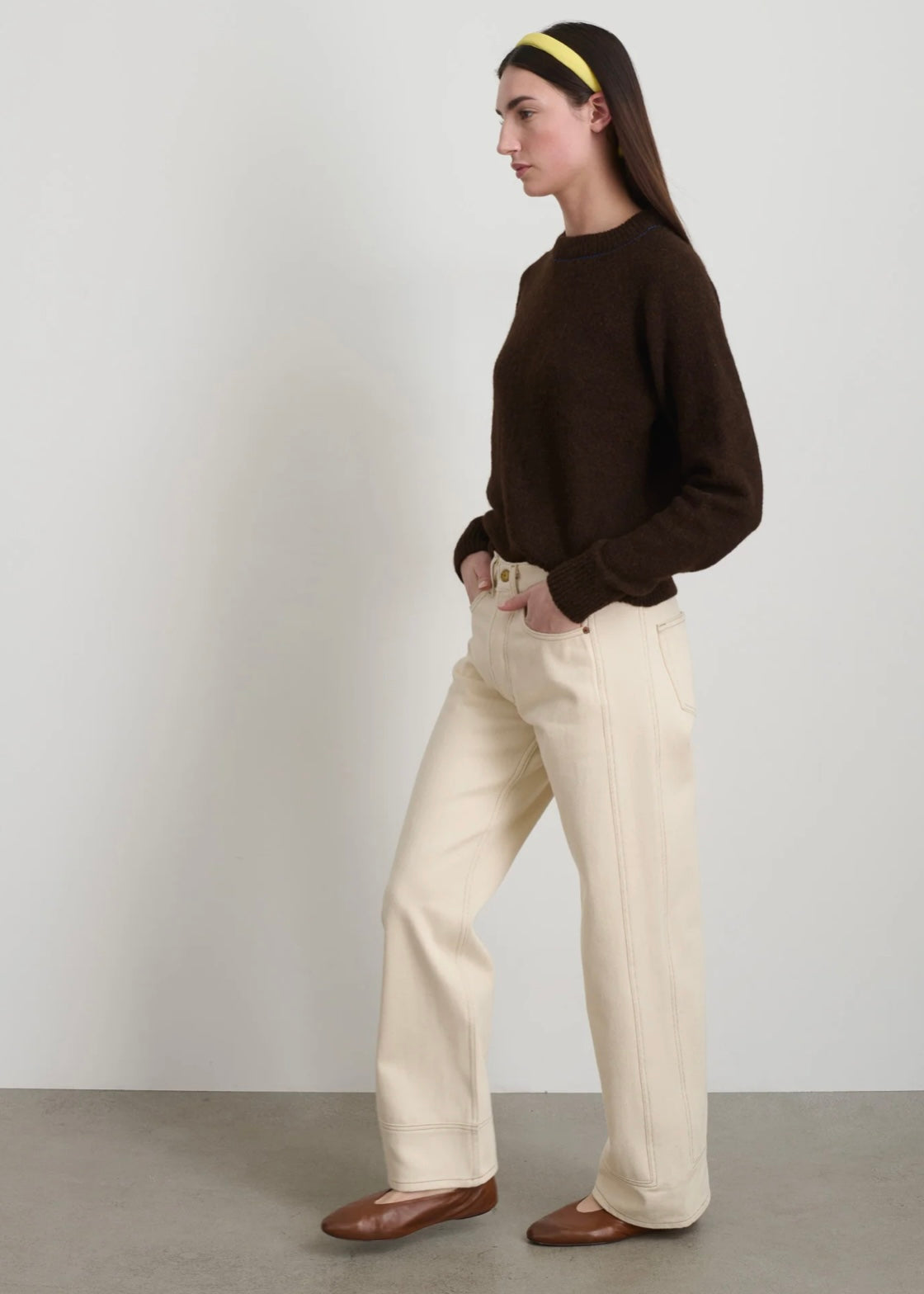 Model is wearing B Sides Charlot jeans, mid-rise relaxed straight denim in undyed cotton, with 5-pocket design, copper rivets, and brass logo button, part of the House of Woven Stories curated collection.