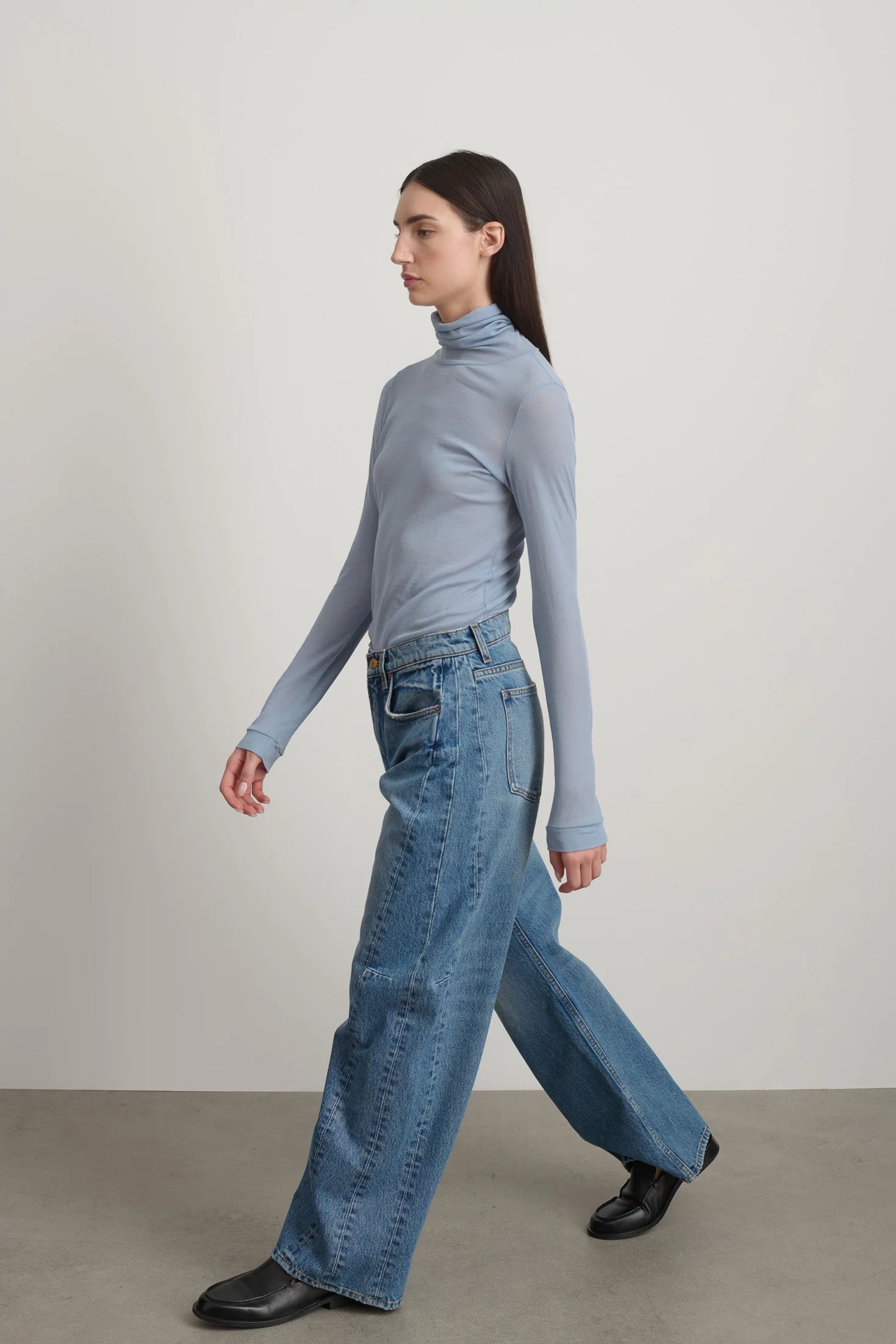 Model is wearing Relaxed Cuffed Lasso Jean Jane Wash by B Sides in pale blue stone washed cotton-rich denim with high waist, pieced outseam, kinked leg and raw hem, available at House of Nomad Stories