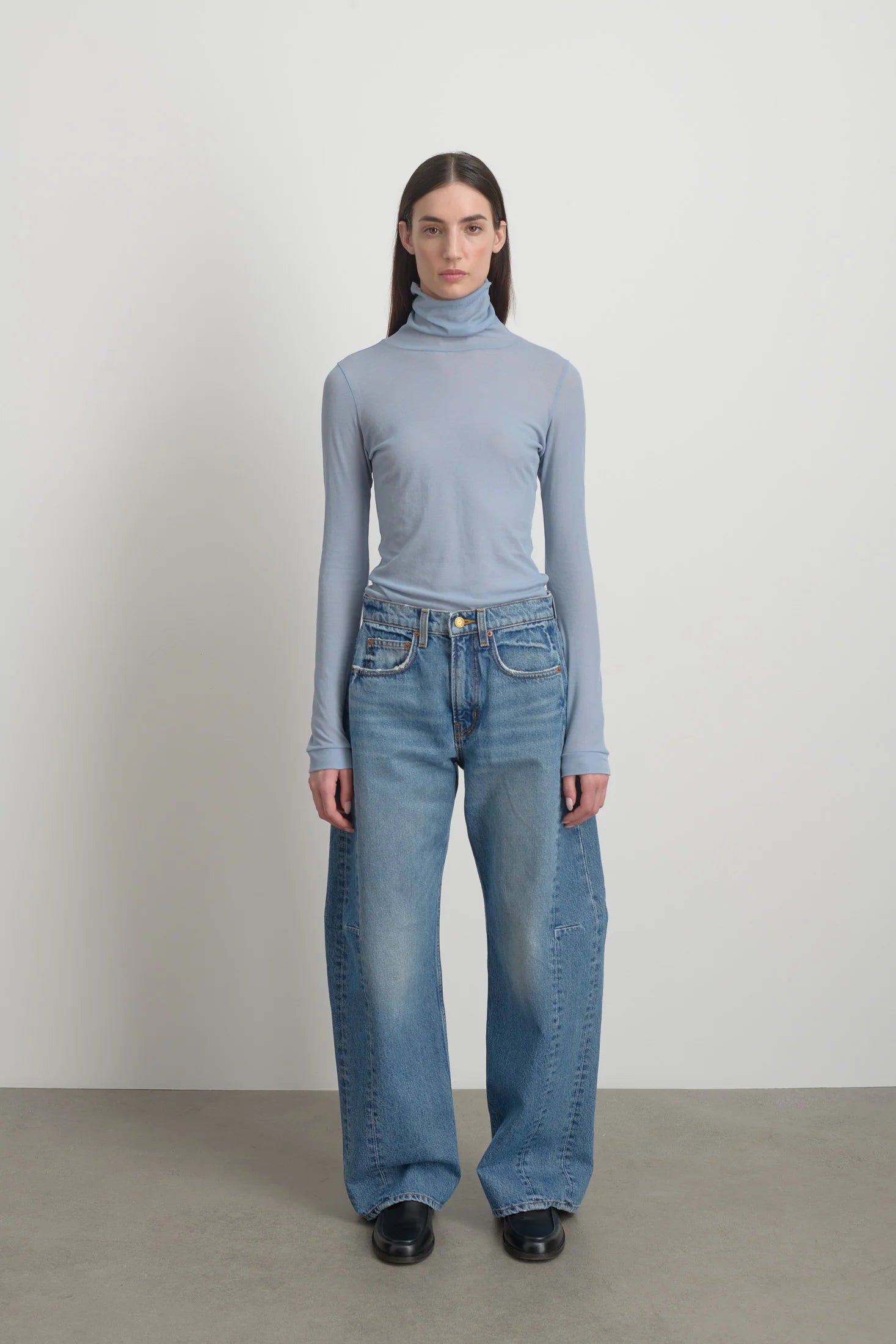Model is wearing Relaxed Cuffed Lasso Jean Jane Wash by B Sides in pale blue stone washed cotton-rich denim with high waist, pieced outseam, kinked leg and raw hem, available at House of Nomad Stories