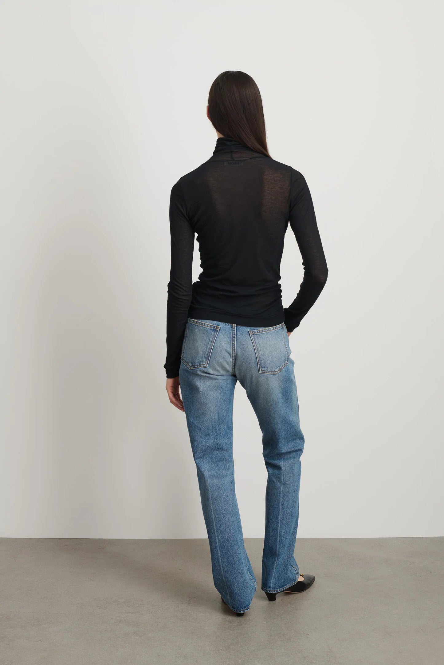 Model is wearing Jana Cotton Turtleneck in Black by B Sides in Japanese-milled black rib crepe with long sleeves, second-skin fit and raw finishing details, available at House of Nomad Stories