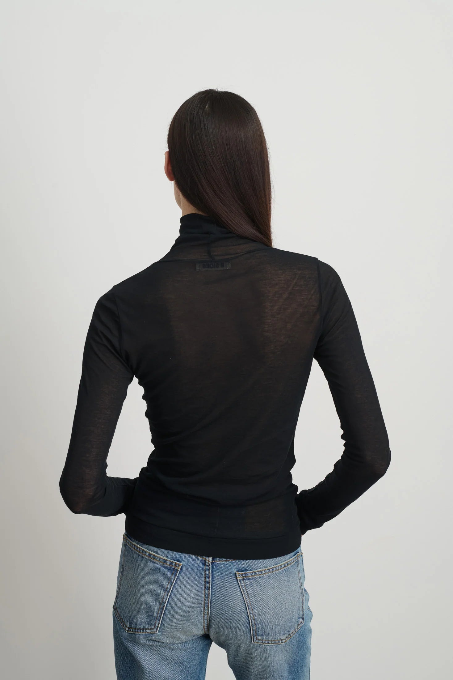 Model is wearing Jana Cotton Turtleneck in Black by B Sides in Japanese-milled black rib crepe with long sleeves, second-skin fit and raw finishing details, available at House of Nomad Stories