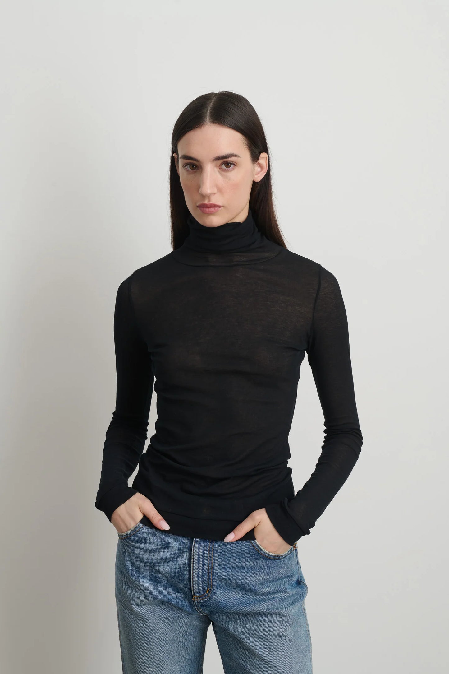 Model is wearing Jana Cotton Turtleneck in Black by B Sides in Japanese-milled black rib crepe with long sleeves, second-skin fit and raw finishing details, available at House of Nomad Stories