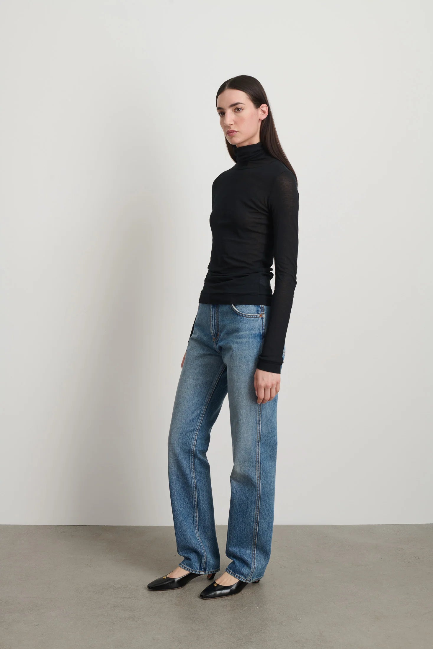 Model is wearing Jana Cotton Turtleneck in Black by B Sides in Japanese-milled black rib crepe with long sleeves, second-skin fit and raw finishing details, available at House of Nomad Stories