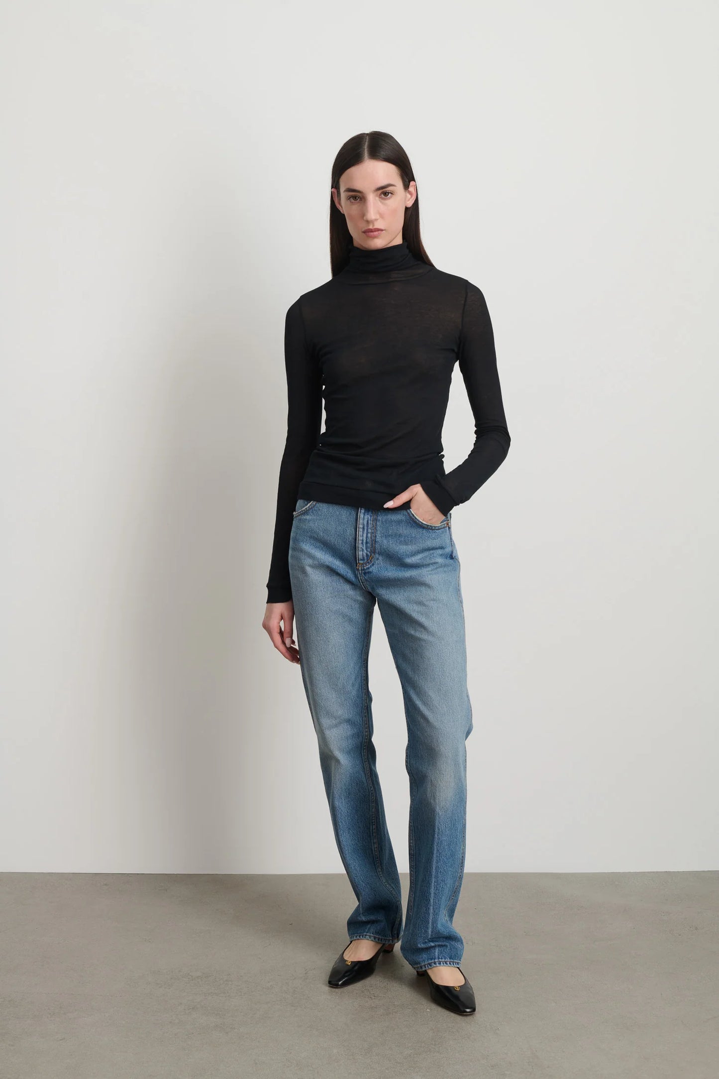 Model is wearing Jana Cotton Turtleneck in Black by B Sides in Japanese-milled black rib crepe with long sleeves, second-skin fit and raw finishing details, available at House of Nomad Stories
