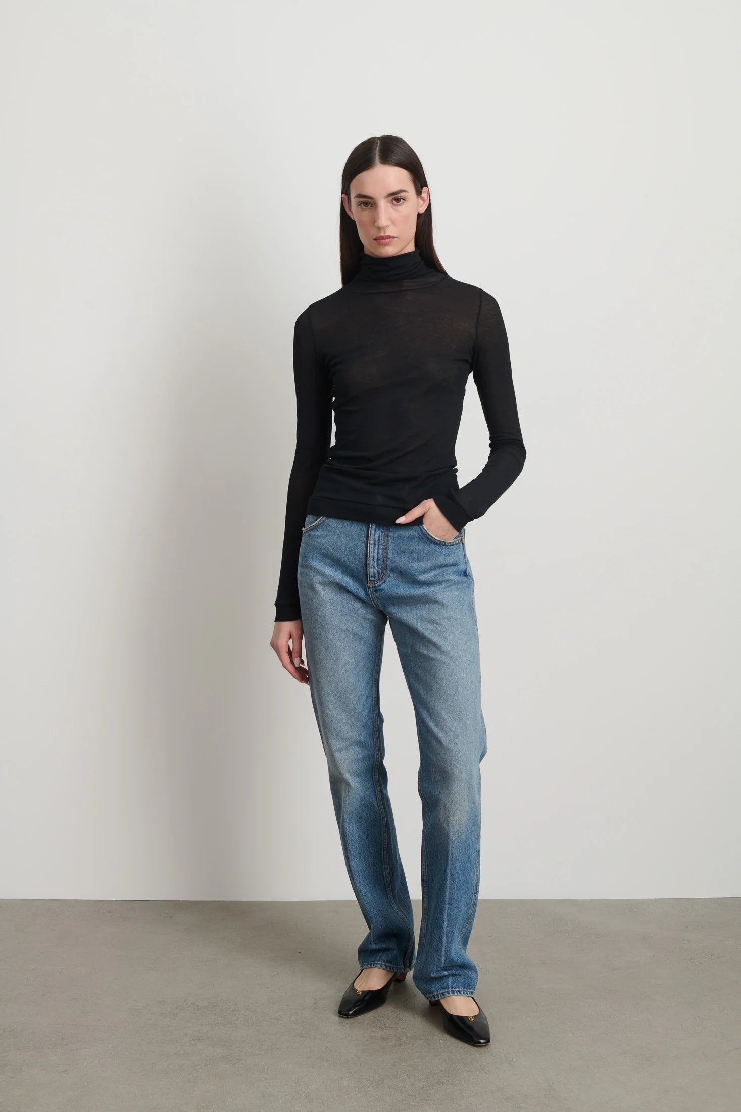 Model is wearing Jana Cotton Turtleneck in Black by B Sides in Japanese-milled black rib crepe with long sleeves, second-skin fit and raw finishing details, available at House of Nomad Stories