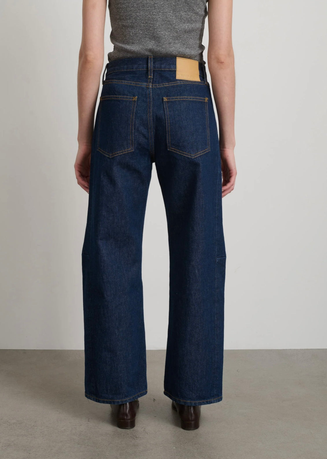 Model is wearing B Sides Lasso Jeans in double-faced Japanese denim, natural waist, kinked leg, cropped length, roped hem, with signature outseam detailing, part of House of Woven Stories curated collection.