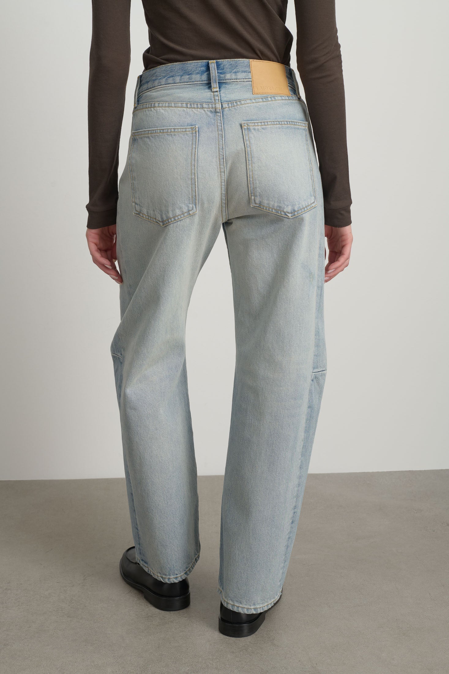 Model is wearing Slim Lasso Cotton Jean Art Wash by B Sides in heavy indigo cotton denim with high waist, pieced outseam, kinked leg and roped hem, available at House of Nomad Stories.