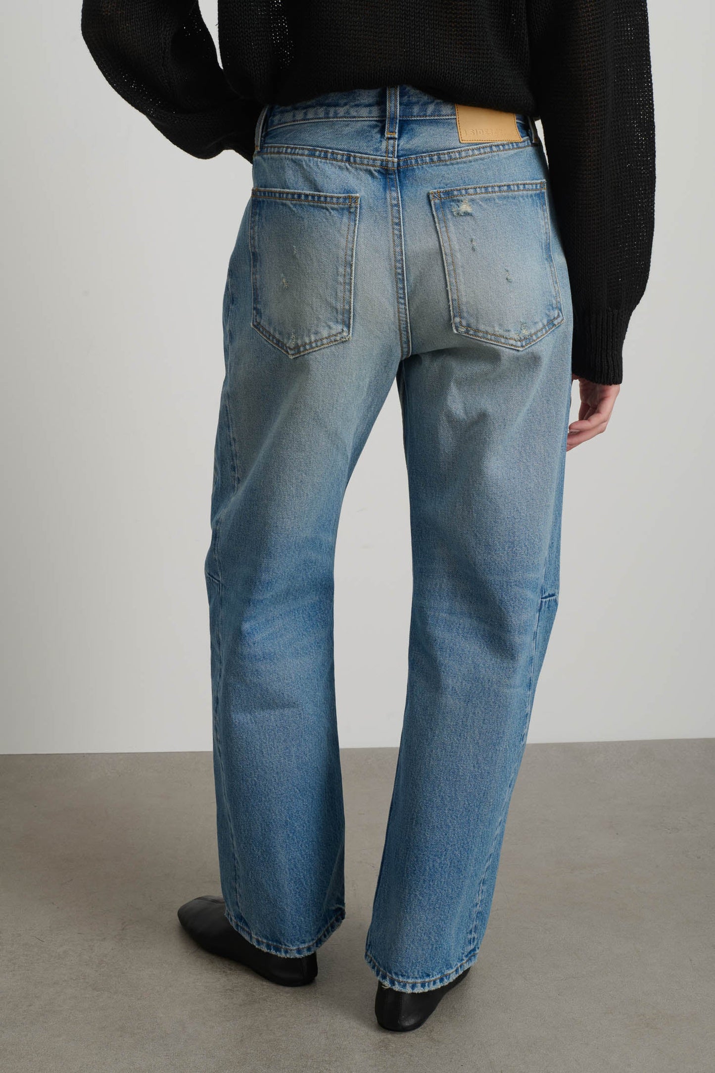 Model is wearing B Sides Slim Lasso Jean in vintage indigo denim, high-rise relaxed kinked leg jeans with 29-inch inseam, stone-washed mid-tone finish, from the curated selection of House of Woven Stories