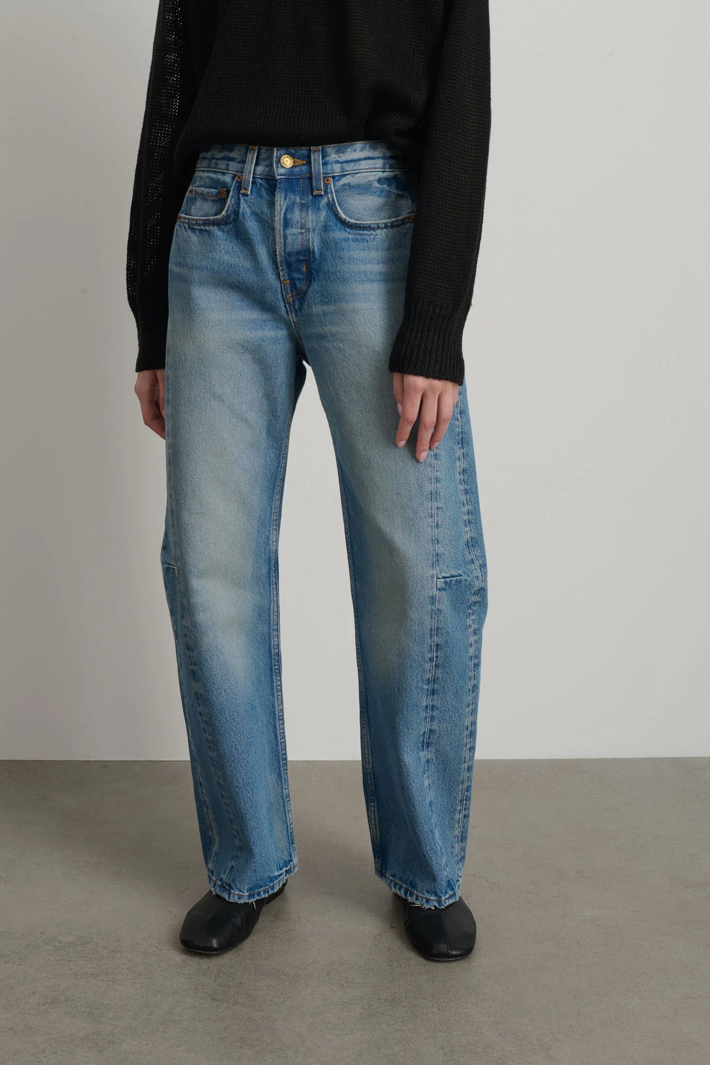 Model is wearing B Sides Slim Lasso Jean in vintage indigo denim, high-rise relaxed kinked leg jeans with 29-inch inseam, stone-washed mid-tone finish, from the curated selection of House of Woven Stories