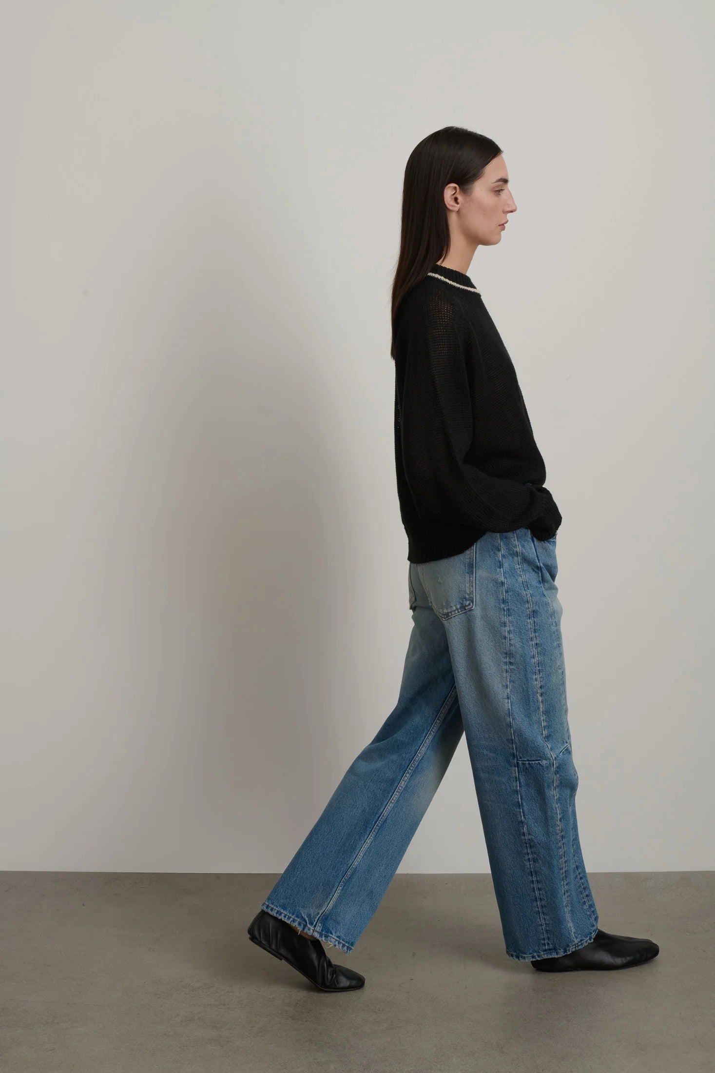 Model is wearing B Sides Slim Lasso Jean in vintage indigo denim, high-rise relaxed kinked leg jeans with 29-inch inseam, stone-washed mid-tone finish, from the curated selection of House of Woven Stories