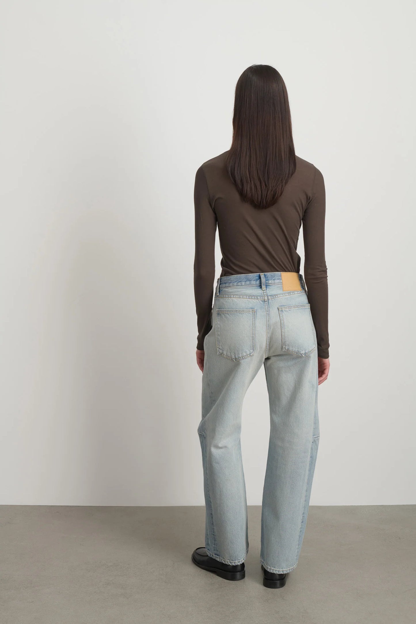 Model is wearing Slim Lasso Cotton Jean Art Wash by B Sides in heavy indigo cotton denim with high waist, pieced outseam, kinked leg and roped hem, available at House of Nomad Stories.