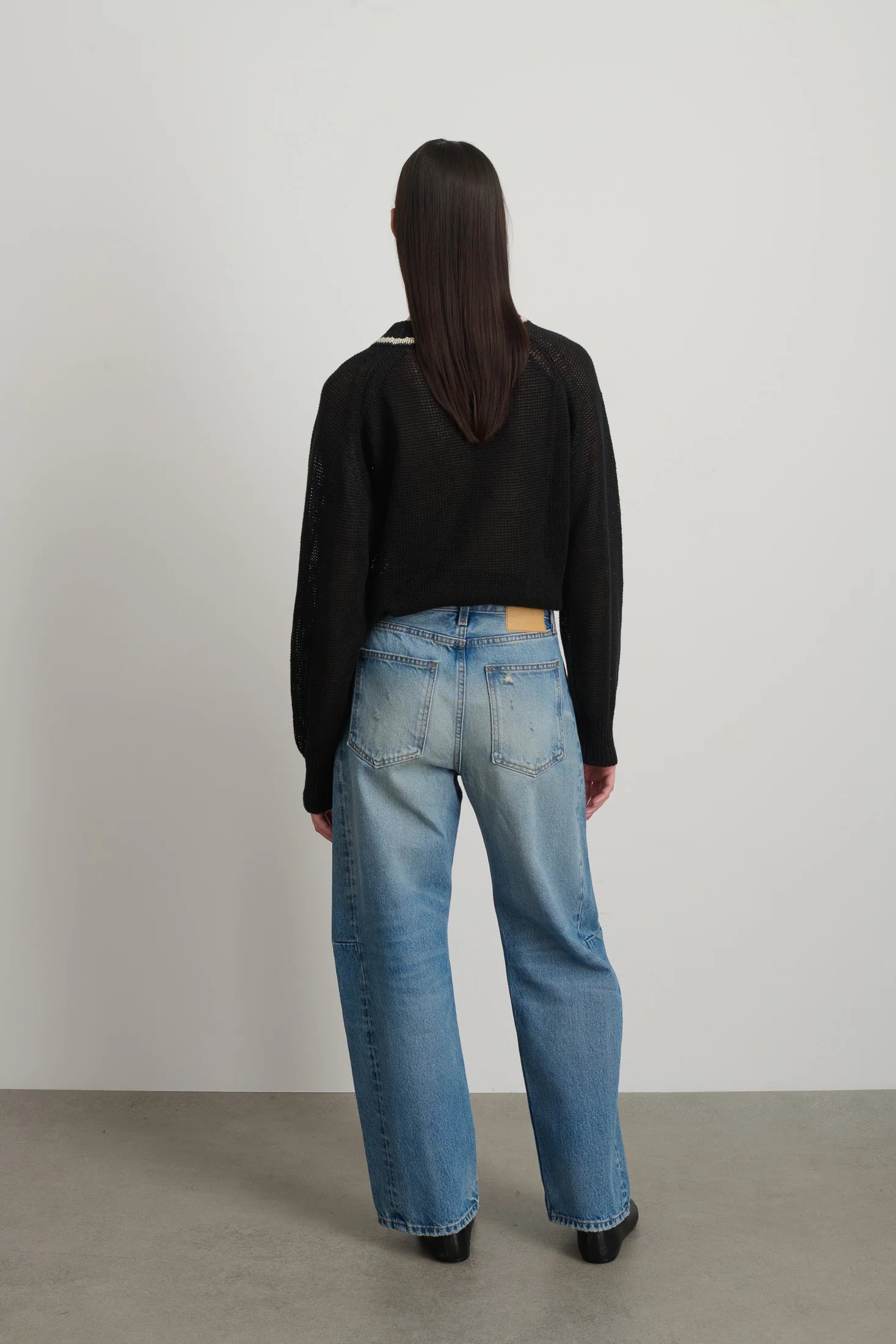 Model is wearing B Sides Slim Lasso Jean in vintage indigo denim, high-rise relaxed kinked leg jeans with 29-inch inseam, stone-washed mid-tone finish, from the curated selection of House of Woven Stories