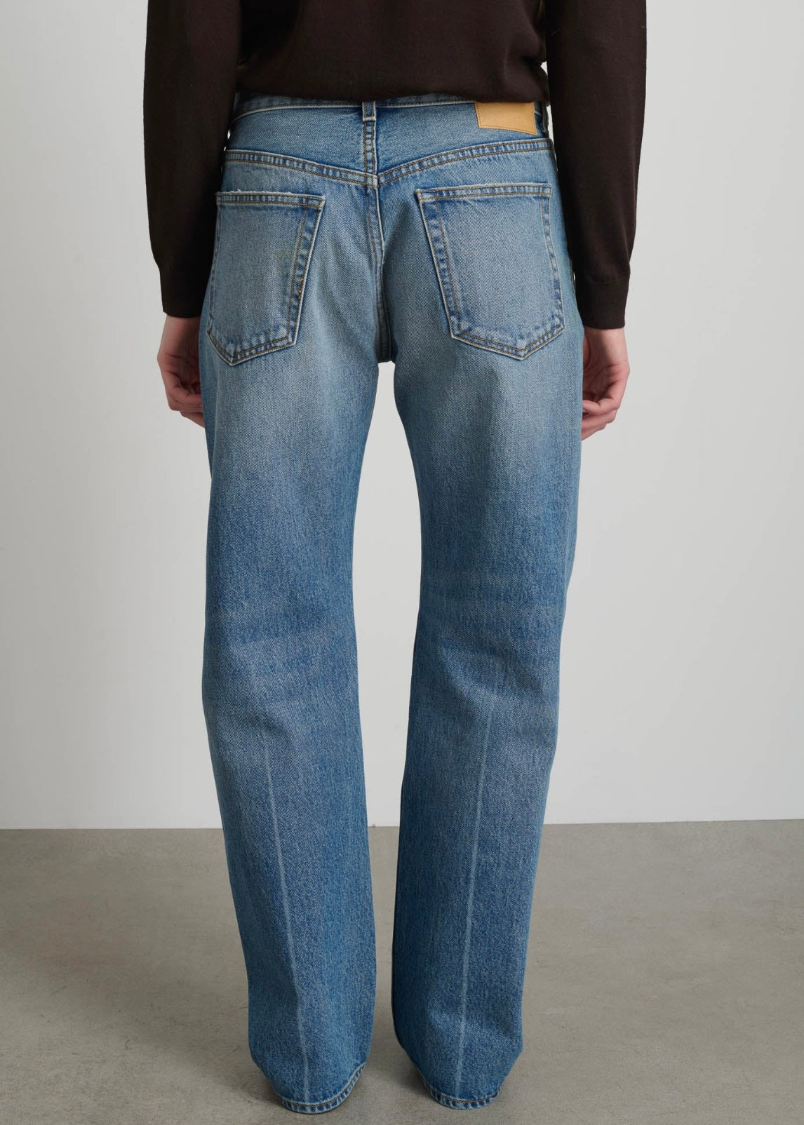Model is wearing B Sides Tilda Jeans, mid-rise draped straight indigo denim with curved inseam, tapered leg, zip fly, and brass button, part of House of Woven Stories curated collection.