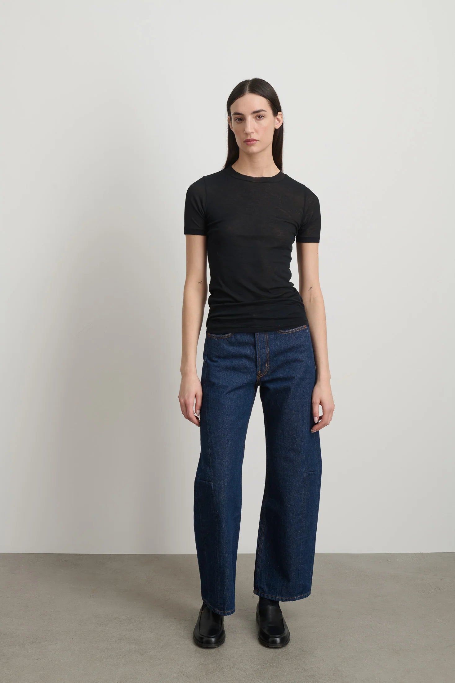 Model is wearing Viven Black Cotton Tee by B Sides in Japanese-milled black rib crepe with slim second-skin fit, short sleeves and crew neck, available at House of Nomad Stories