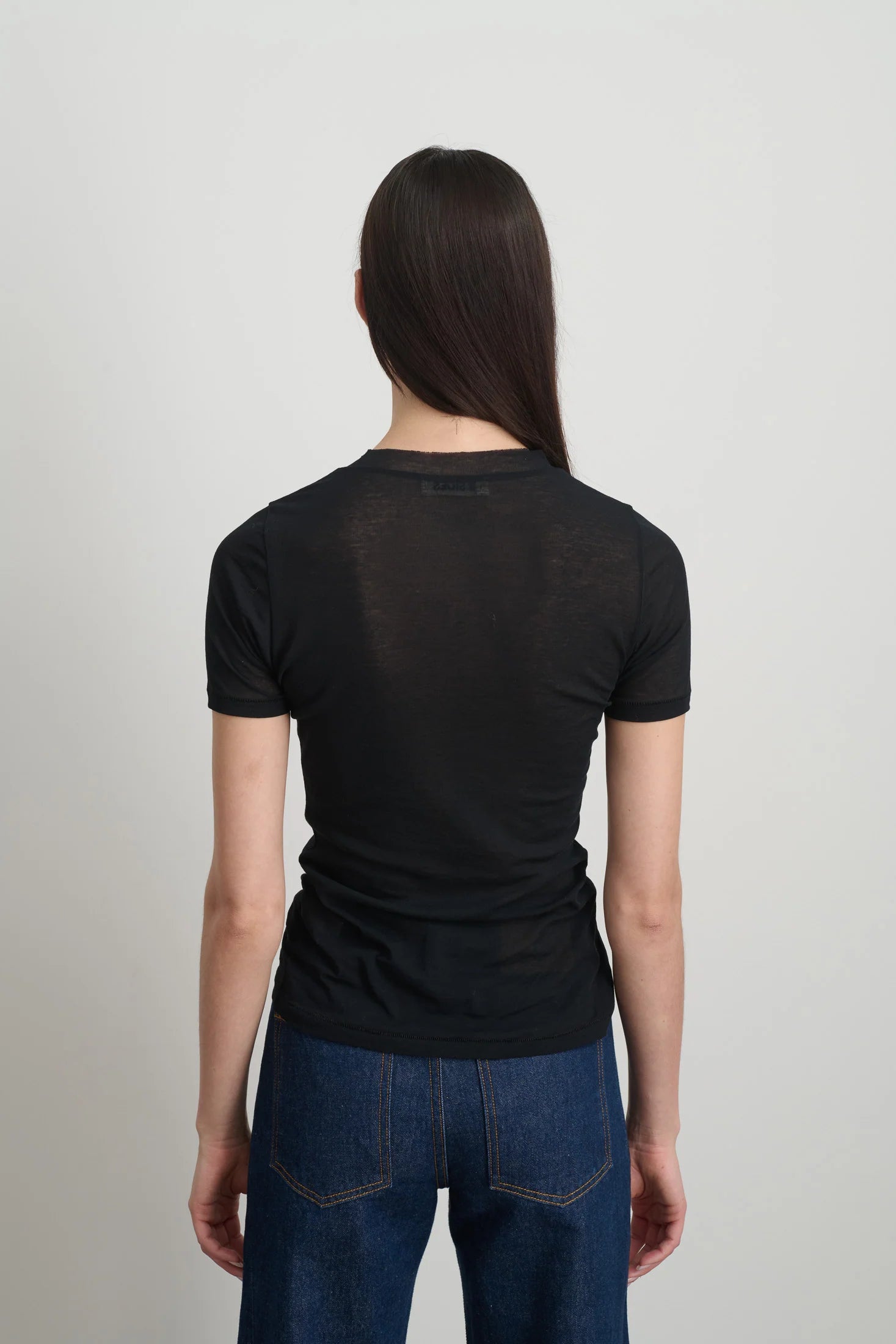 Model is wearing Viven Black Cotton Tee by B Sides in Japanese-milled black rib crepe with slim second-skin fit, short sleeves and crew neck, available at House of Nomad Stories