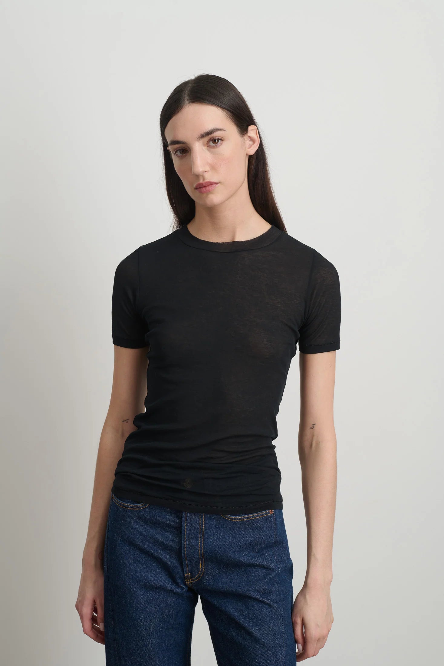Model is wearing Viven Black Cotton Tee by B Sides in Japanese-milled black rib crepe with slim second-skin fit, short sleeves and crew neck, available at House of Nomad Stories