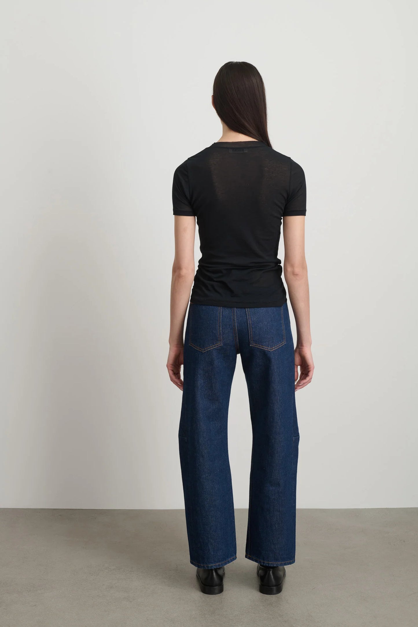 Model is wearing Viven Black Cotton Tee by B Sides in Japanese-milled black rib crepe with slim second-skin fit, short sleeves and crew neck, available at House of Nomad Stories