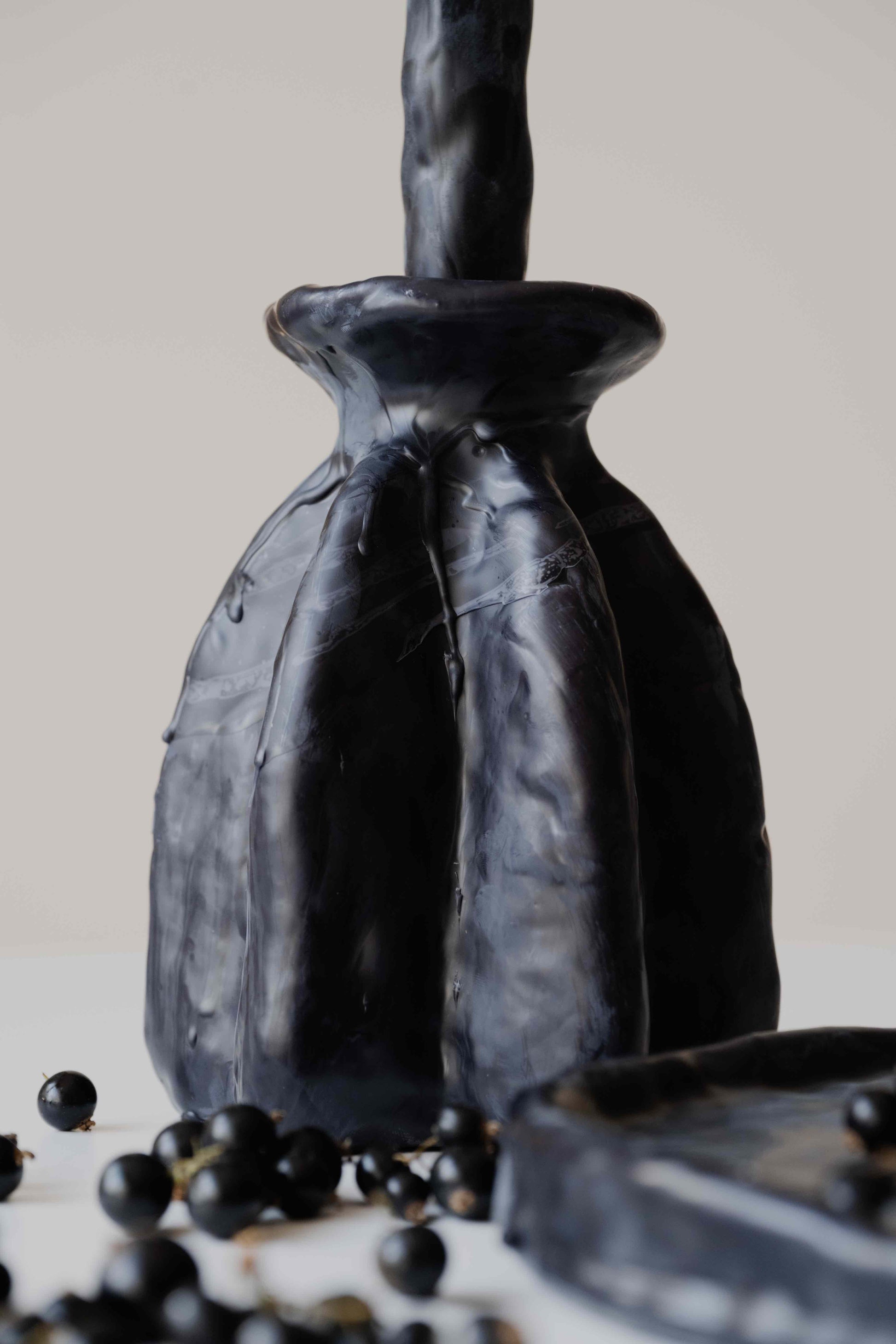 Carambola Low in Black candle holder by Oberflacht, part of the House of Woven Stories selection, handmade from beeswax and paraffin with matching twig candle and natural variations in colour and texture.