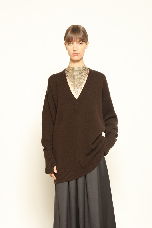 Model is wearing the Chocolate Nina V-Neck Long Sweater by House of Woven Stories, crafted from 100% pure Inner Mongolia cashmere in a deep chocolate shade, featuring an elongated silhouette, deep V-neckline, soft breathable knit, and timeless sustainable Italian luxury design