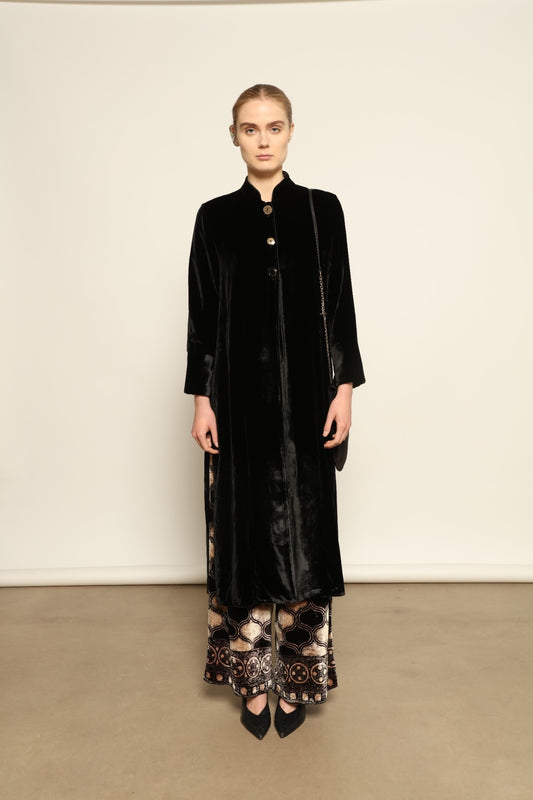 Model is wearing the Cleo Black Long Jacket VR.40 by Obidi, crafted from luxurious velvet with a structured silhouette and refined texture, combining artisanal craftsmanship with contemporary style.