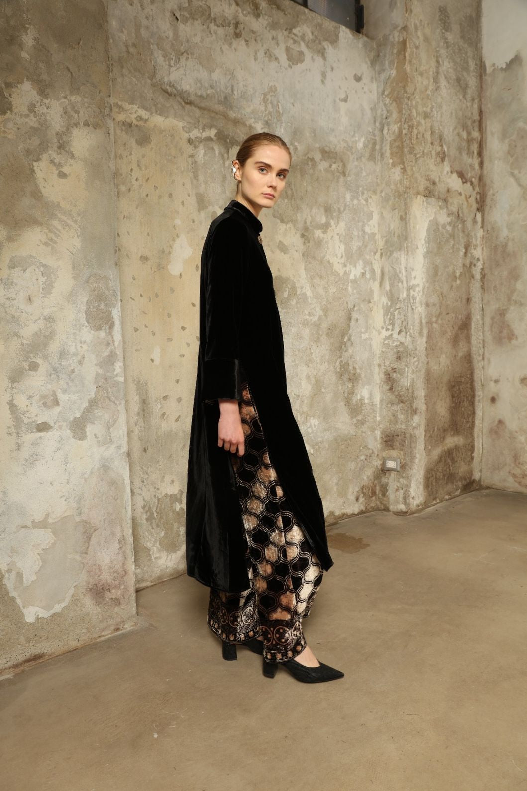 Model is wearing the Cleo Black Long Jacket VR.40 by Obidi, crafted from luxurious velvet with a structured silhouette and refined texture, combining artisanal craftsmanship with contemporary style.
