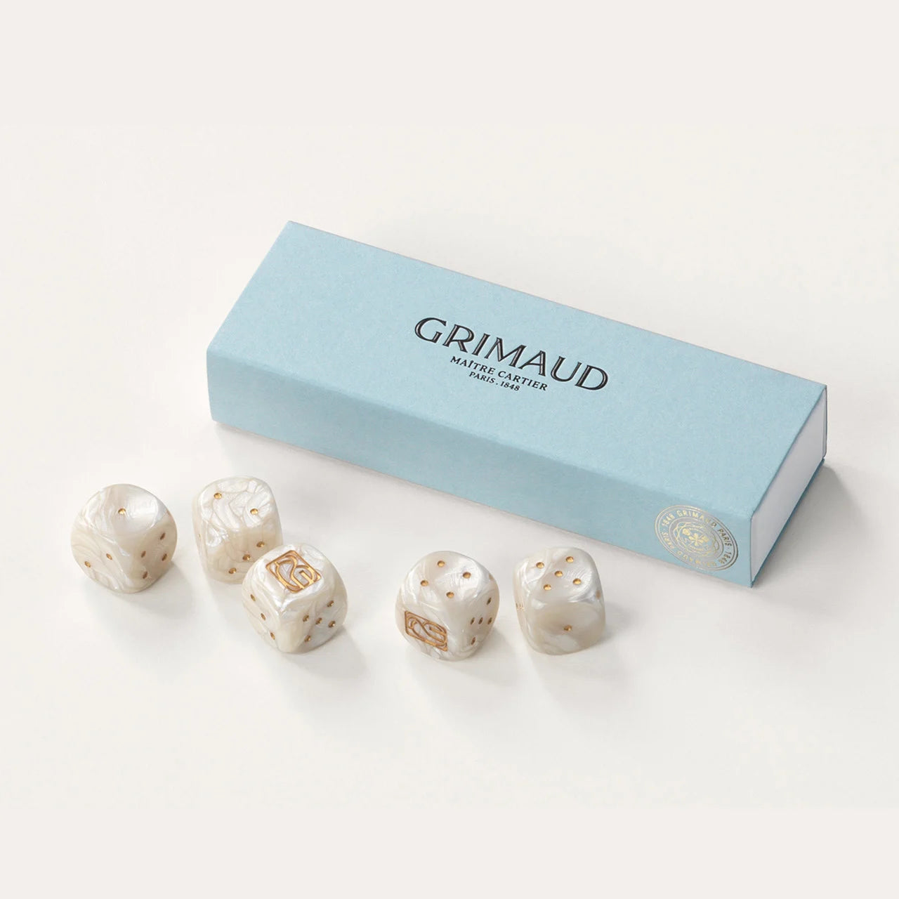 Coffret de dés Grimaud Paris from the House of Woven Stories selection, luxury 5 dice set made in France, white resin dice with gold pips in a Dolphin Blue case.