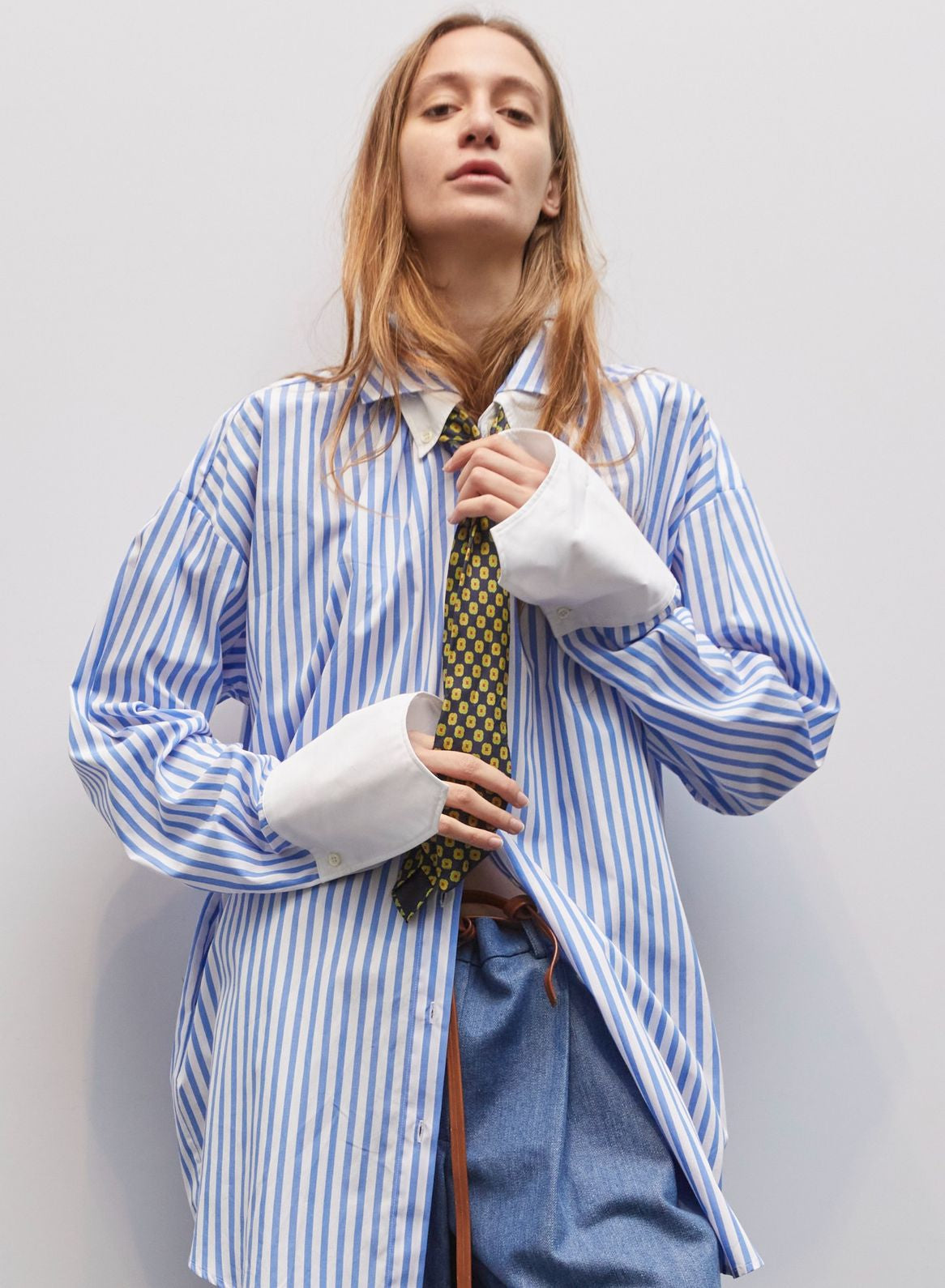 Model wearing the Crazy Cotton Shirt by Maison Jejia, featuring bold vertical stripes, crisp white cuffs, sharp collar, relaxed tailored fit, and playful yet classic design, part of the House of Woven Stories Selection