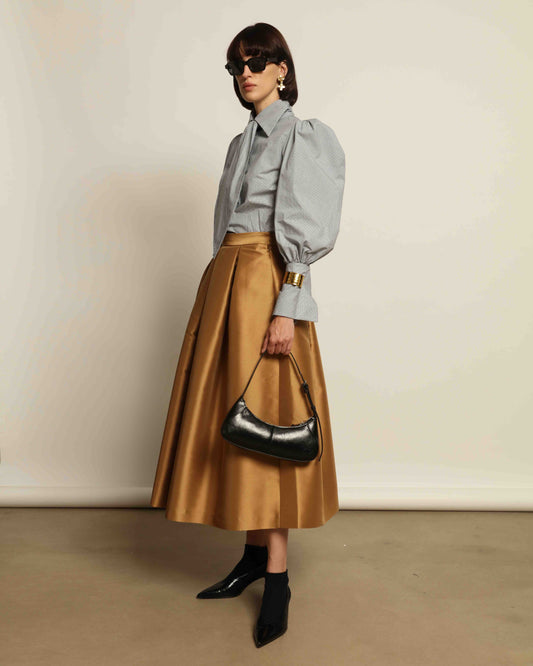Model is wearing Duchesse Camel Skirt by Lunatica Milano, part of House of Woven Stories selection. Flowing pleated maxi skirt crafted from a sumptuous soft-blend fabric. Timelessly elegant, feminine, and handmade in Italy.