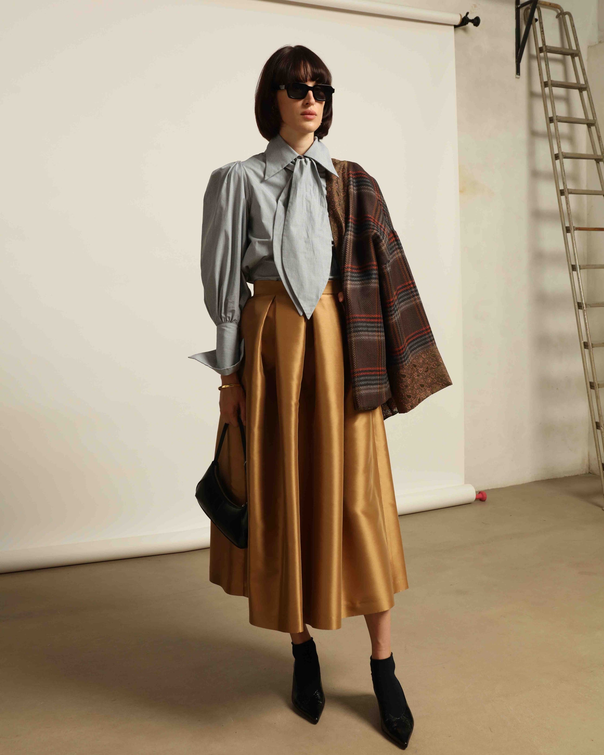 Model is wearing Duchesse Camel Skirt by Lunatica Milano, part of House of Woven Stories selection. Flowing pleated maxi skirt crafted from a sumptuous soft-blend fabric. Timelessly elegant, feminine, and handmade in Italy.