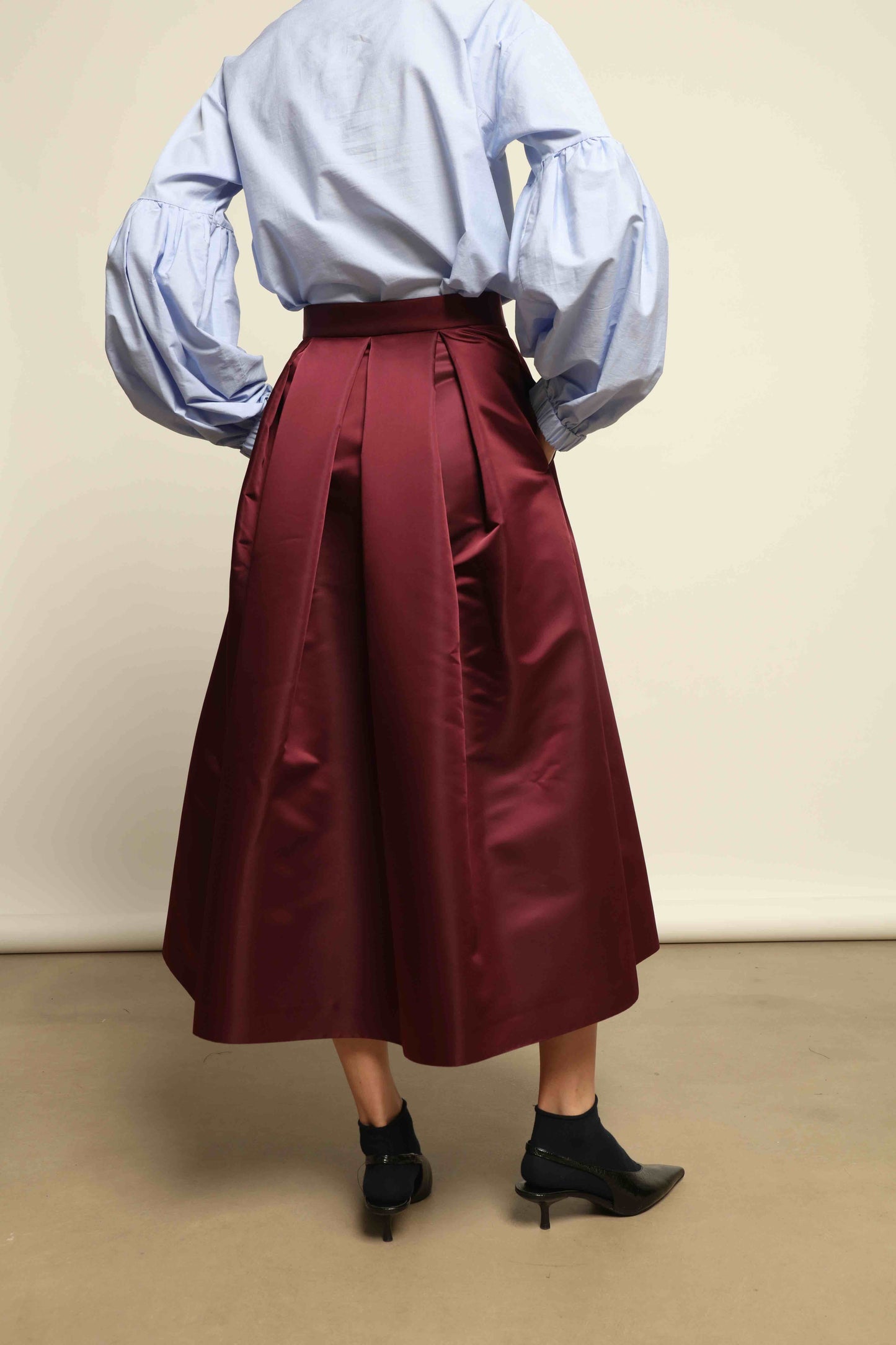 Model is wearing the Duchesse Violet Skirt by Lunatica Milano in mirtillo purple with box pleats and a flowing, elegant silhouette.