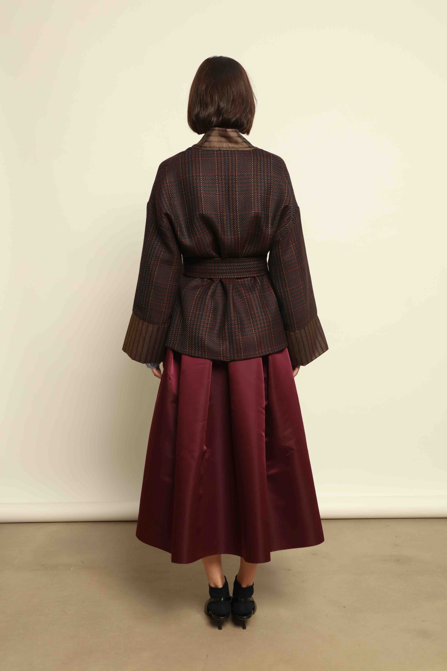 Model is wearing the Duchesse Violet Skirt by Lunatica Milano in mirtillo purple with box pleats and a flowing, elegant silhouette.