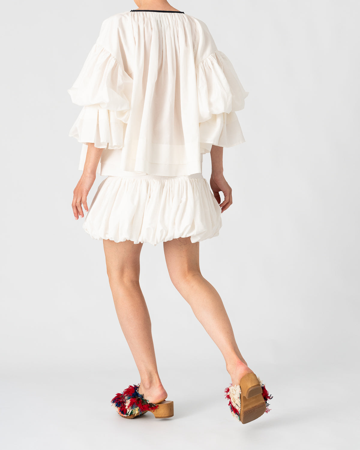 Model is wearing the Favignana Cotton and Silk Blouse by Les Vacances d’Irina, a vintage-inspired handmade blouse with pleated three-quarter sleeves, black bow neckline, and luxurious cotton-silk fabric, available at House of Woven Stories.