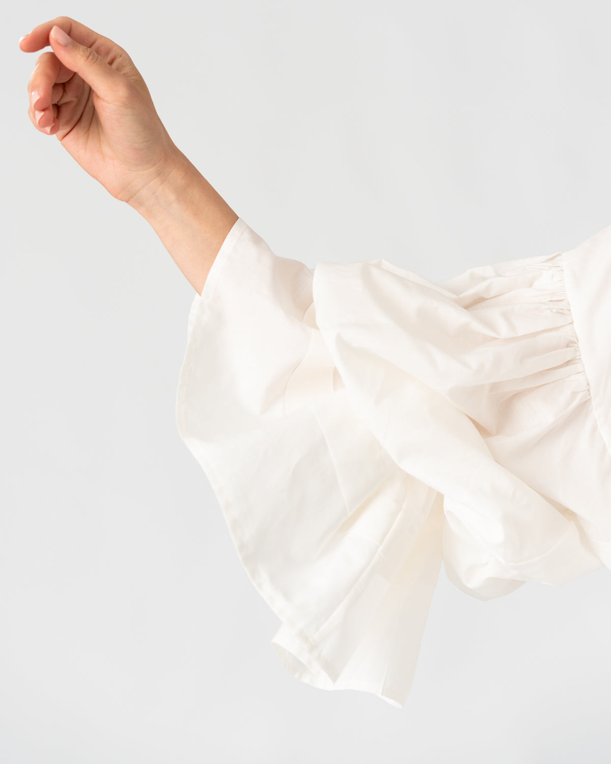 Model is wearing the Favignana Cotton and Silk Blouse by Les Vacances d’Irina, a vintage-inspired handmade blouse with pleated three-quarter sleeves, black bow neckline, and luxurious cotton-silk fabric, available at House of Woven Stories.