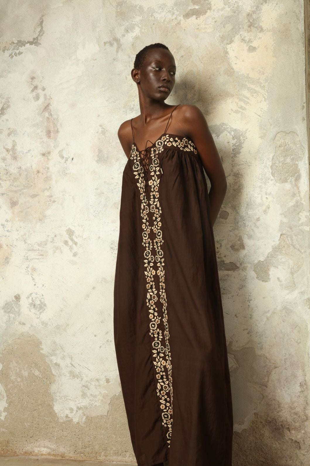 Model is wearing the Flor Brown Linen Dress by Supernaturae x HONS, crafted in heavyweight sustainable linen with a wrap-tie silhouette, earthy brown plant-dyed finish and structured yet breathable form. Made in collaboration with artisan communities in Kutch, Gujarat, this ethical resortwear piece features organic tonal variations and timeless design