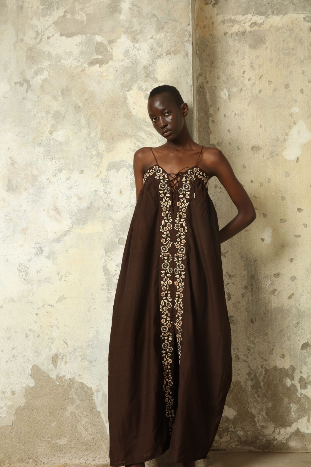 Model is wearing the Flor Brown Linen Dress by Supernaturae x HONS, crafted in heavyweight sustainable linen with a wrap-tie silhouette, earthy brown plant-dyed finish and structured yet breathable form. Made in collaboration with artisan communities in Kutch, Gujarat, this ethical resortwear piece features organic tonal variations and timeless design