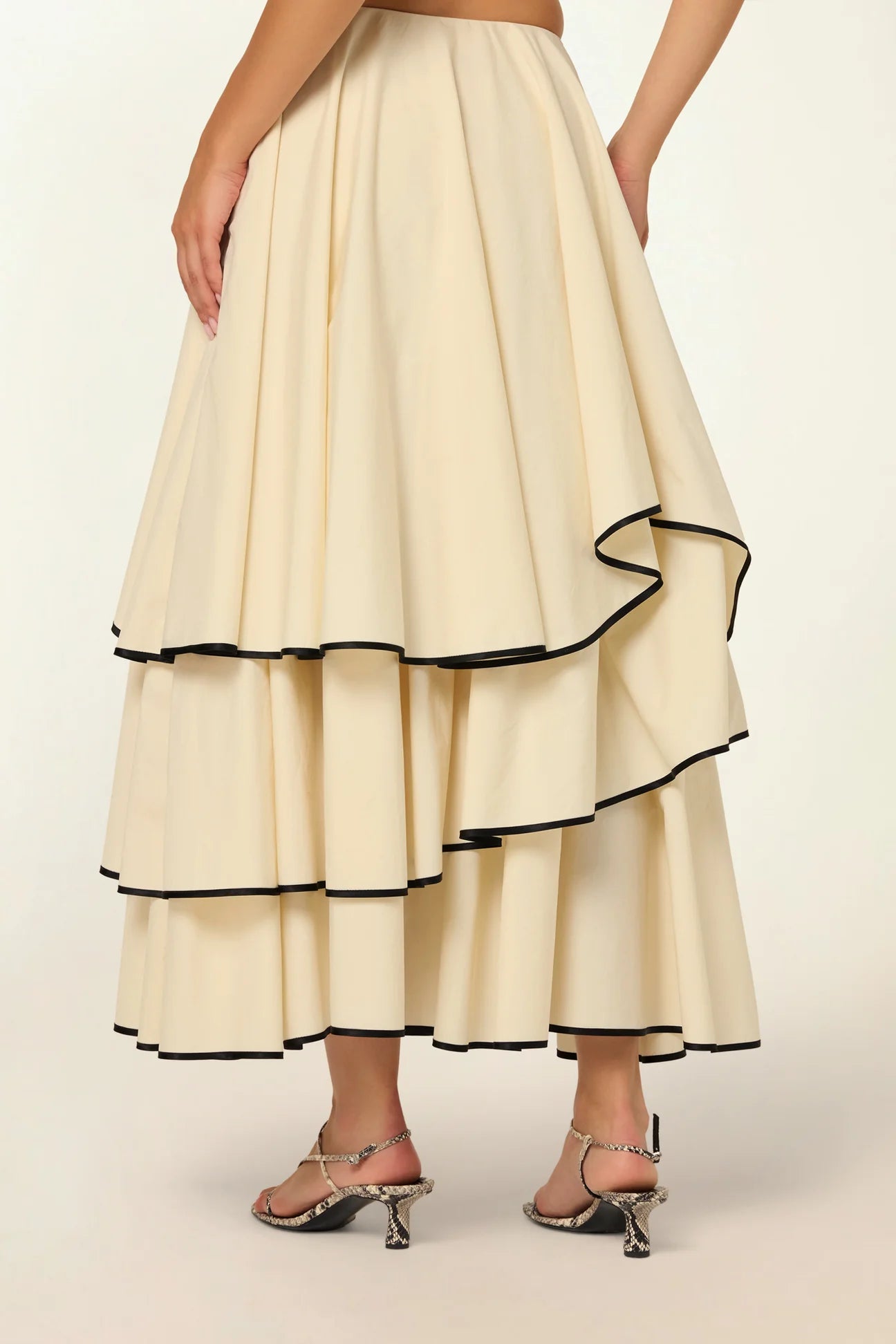 Model wearing a Frill Layer Skirt by Abadia from the House of Nomad Stories collection, featuring layered frill detailing, soft volume, and a flowing cotton blend silhouette with elegant movement.