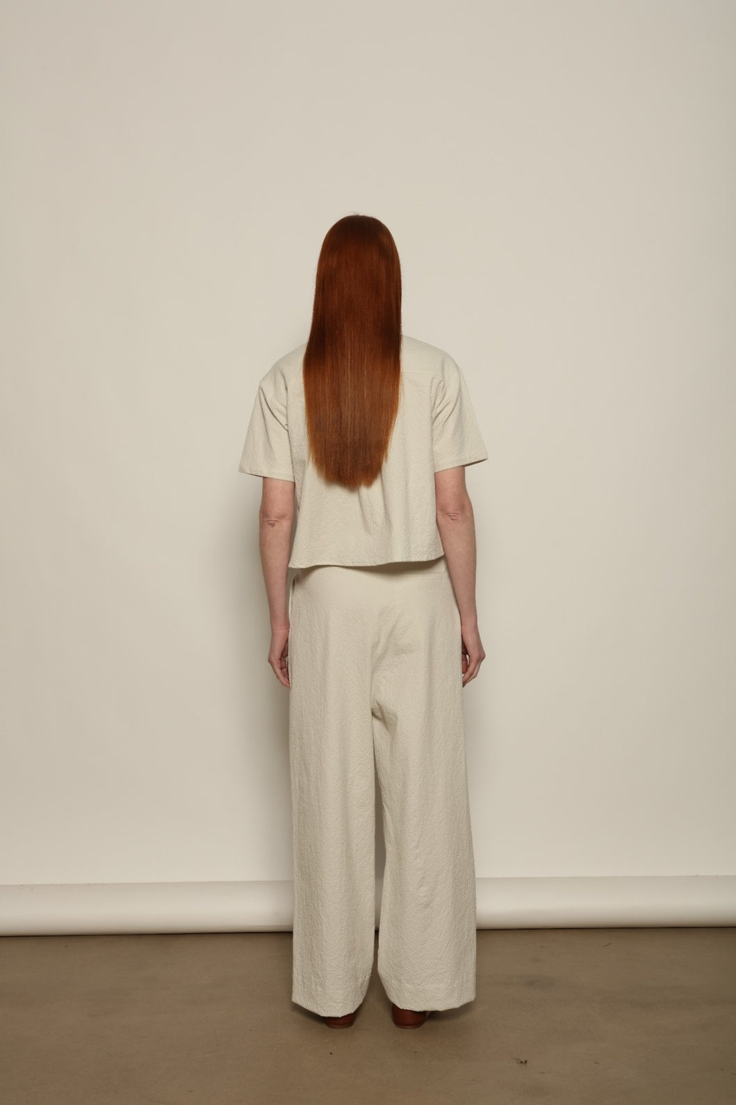 Model is wearing the Gabriella seersucker trousers from the House of Woven Stories selection, lightweight and breathable women’s summer pants made in Italy, featuring a relaxed tailored silhouette designed for effortless movement and warm weather.