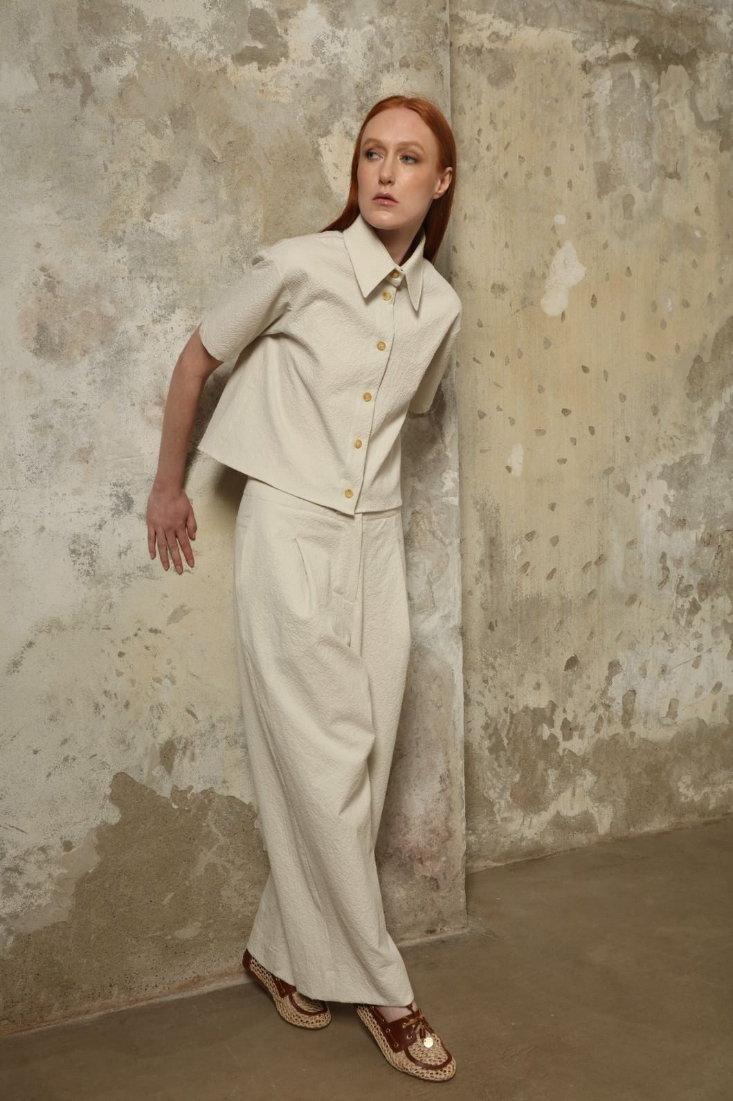Model is wearing the Gabriella seersucker trousers from the House of Woven Stories selection, lightweight and breathable women’s summer pants made in Italy, featuring a relaxed tailored silhouette designed for effortless movement and warm weather.