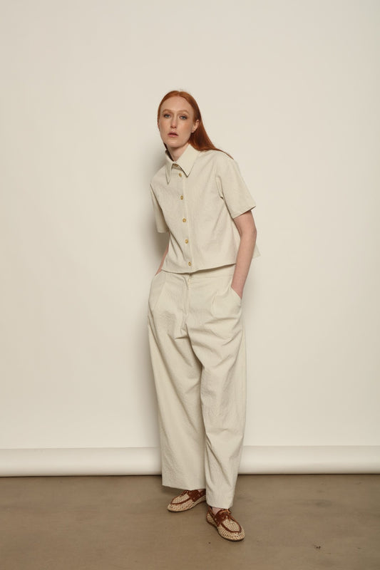 Model is wearing the Gabriella seersucker trousers from the House of Woven Stories selection, lightweight and breathable women’s summer pants made in Italy, featuring a relaxed tailored silhouette designed for effortless movement and warm weather.