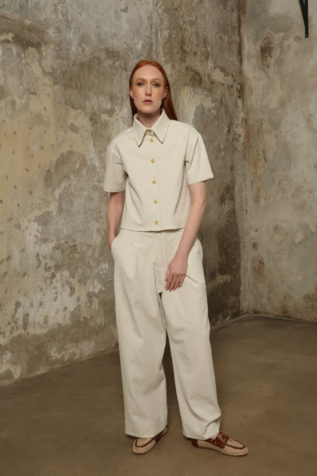 Model is wearing the Gabriella seersucker trousers from the House of Woven Stories selection, lightweight and breathable women’s summer pants made in Italy, featuring a relaxed tailored silhouette designed for effortless movement and warm weather.