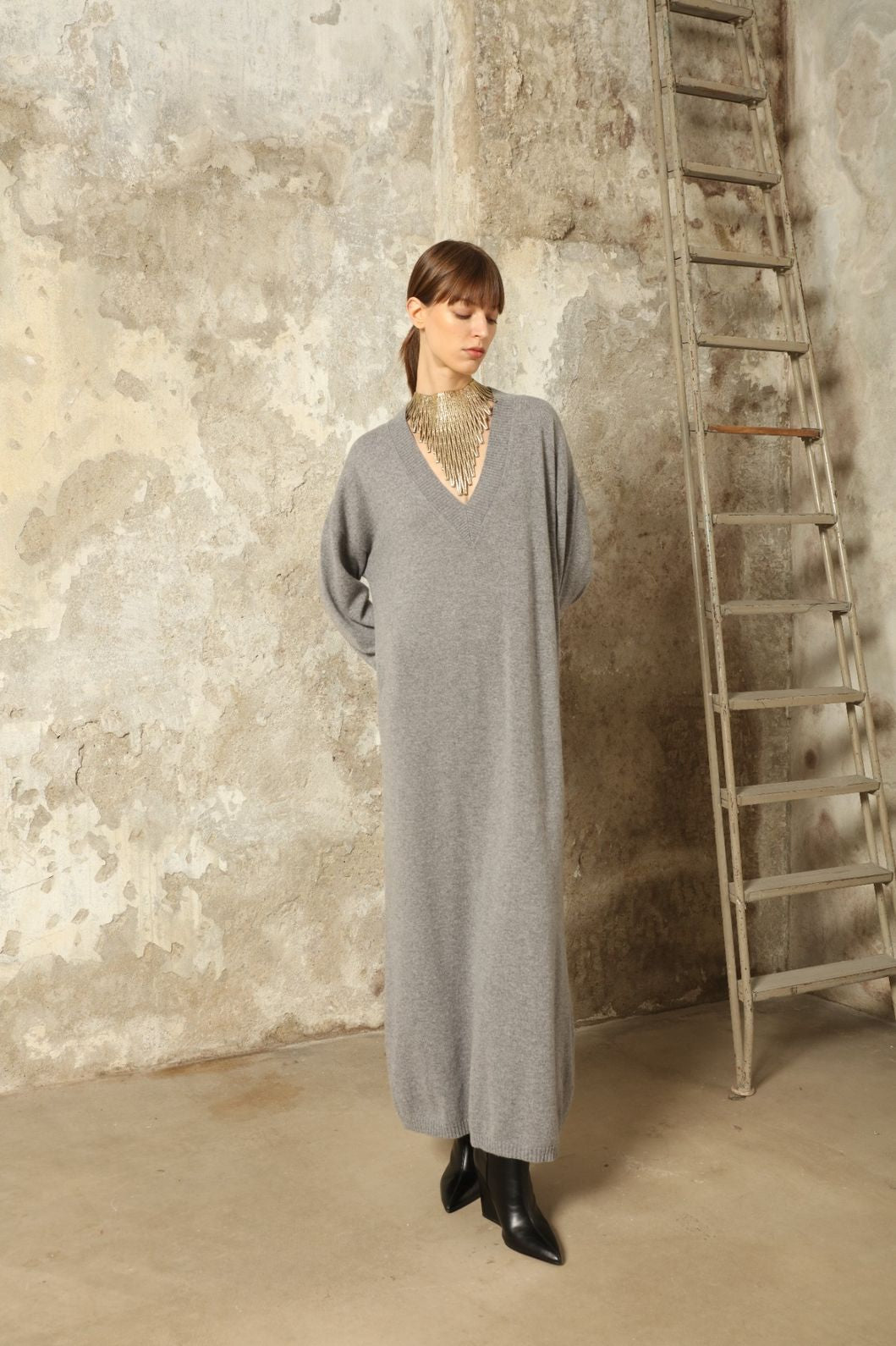 Model is wearing the Graphite Katharina V-Neck Cashmere Maxi Dress by House of Woven Stories, made from 100% pure Inner Mongolia cashmere, featuring a soft, breathable, warm knit with a long flowing silhouette, deep V-neckline, and timeless ethical luxury craftsmanship