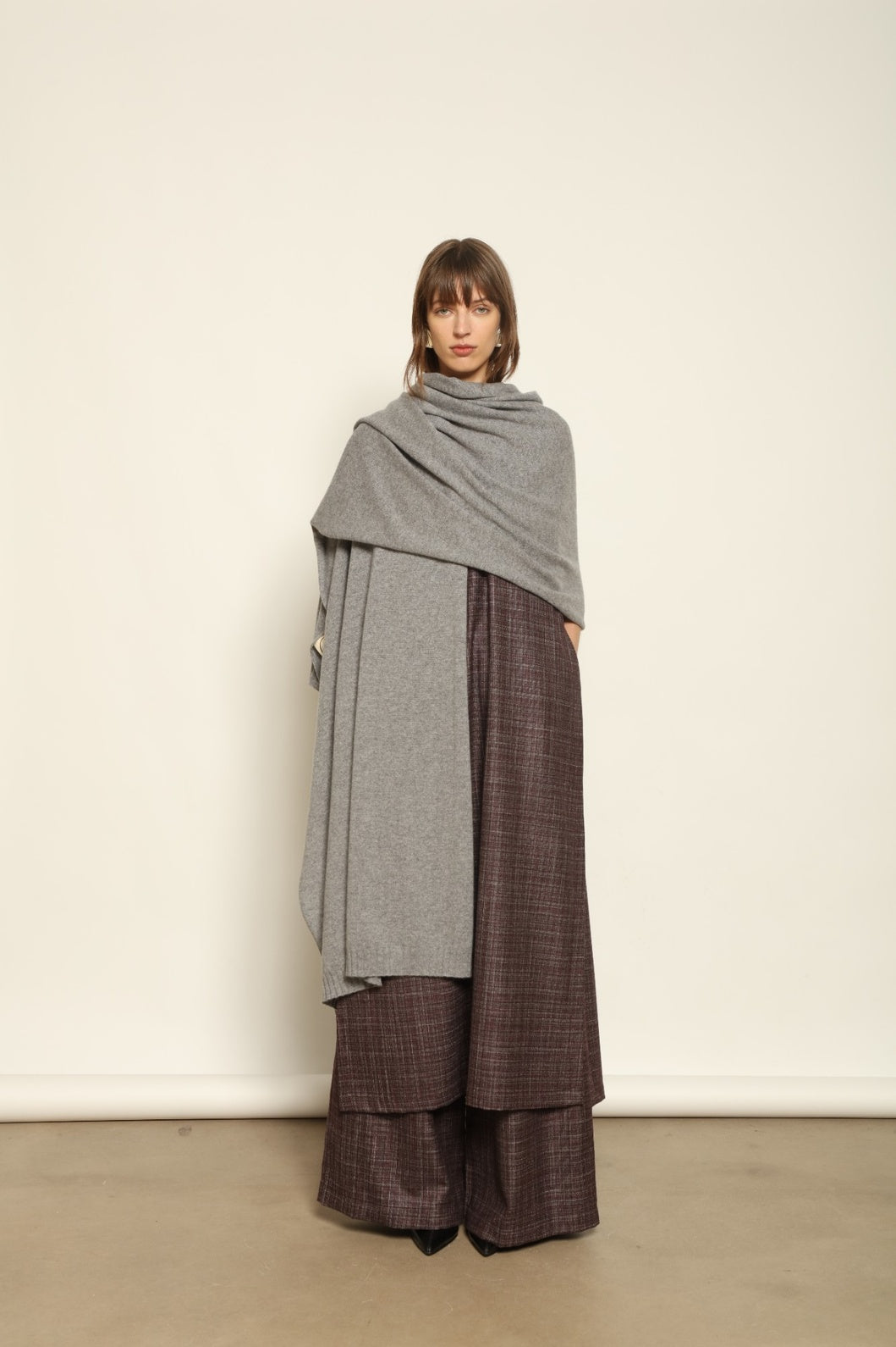 Model wearing the Graphite Leni Cashmere Scarf by House of Woven Stories, made from 100% pure Inner Mongolia cashmere, featuring a soft graphite color, lightweight drape, smooth texture, lasting warmth, and sustainable luxury craftsmanship