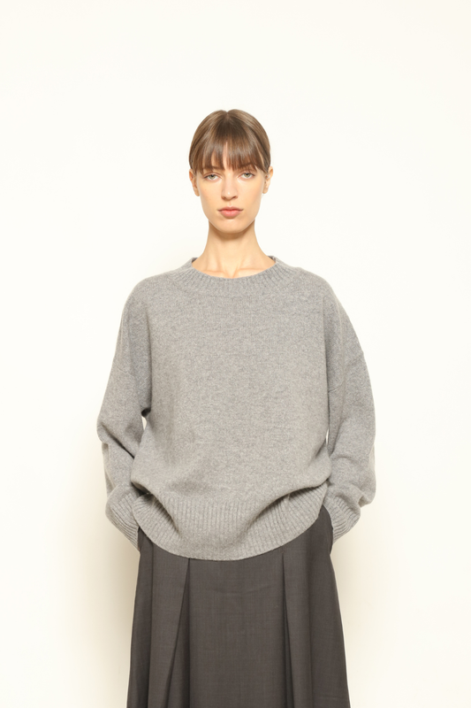 Model is wearing the graphite Noemi Round Neck Pullover by House of Woven Stories, crafted from 100% pure Inner Mongolia cashmere, featuring ultra-soft, breathable, durable knitwear, relaxed fit, round neckline, and timeless ethical luxury design
