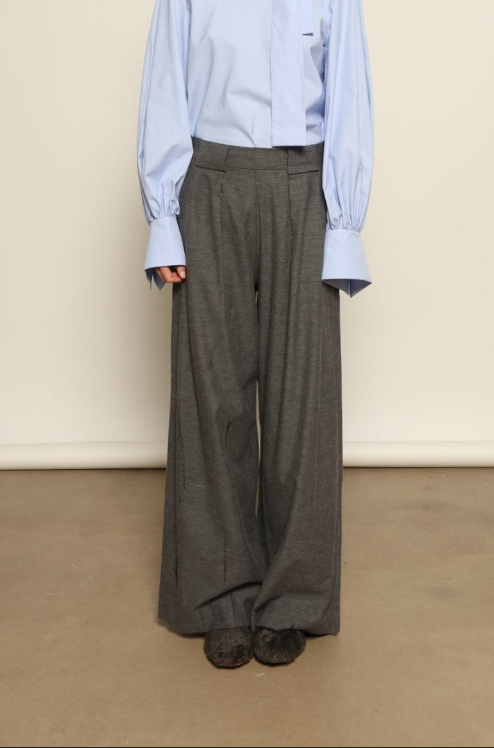 Model is wearing Grey Melange Parigi Wool Trousers by House of Woven Stories, part of the curated House of Woven Stories selection, crafted in Italy from soft cotton flannel with mid-rise waist, front pleats, and wide-leg silhouette for refined comfort.