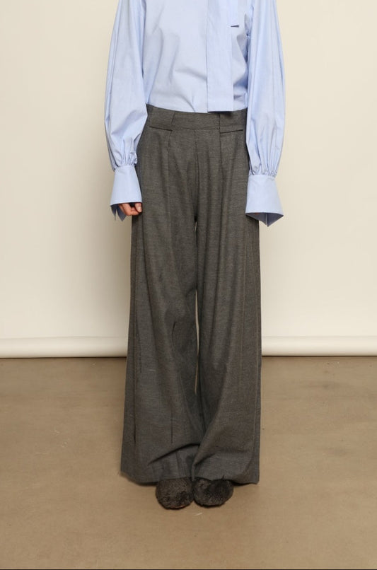 Model is wearing Grey Melange Parigi Wool Trousers by House of Woven Stories, part of the curated House of Woven Stories selection, crafted in Italy from soft cotton flannel with mid-rise waist, front pleats, and wide-leg silhouette for refined comfort.
